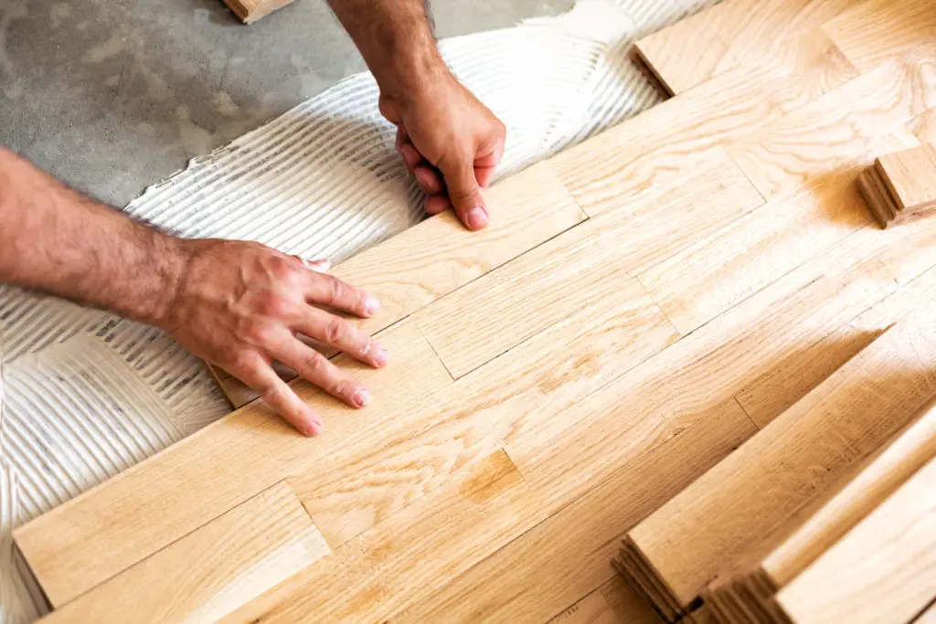 Nahaufnahme der Parkettverlegung in Frankfurt-Bornheim, ein Handwerker legt sorgfältig Holzlamellen.